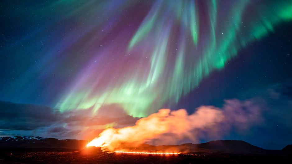 A view of the eruption area with the northern lights dancing in the sky near the town of Grindavik, Iceland, Tuesday April 16, 2024. The volcano in southwestern Iceland that erupted three times in December, January and February, sending lava towards a nearby community, keeps erupting. (AP Photo/Marco di Marco)