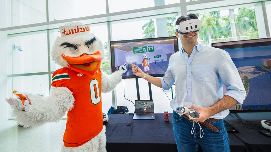 Joao Ribeiro, a staff member who helped create the FYD app, demonstrates glass blowing with University mascot Sebastian the Ibis, who is featured throughout the app. 