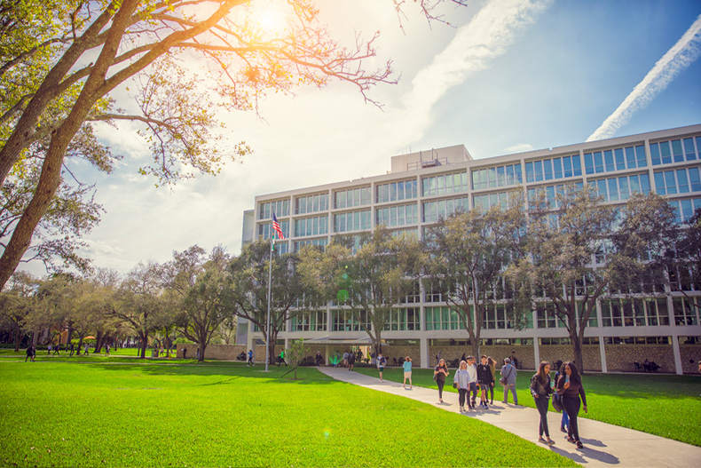 Students walk along a pathway between the Ashe Administration Building and Dooly Memorial Classroom Building on the Coral Gables Campus.