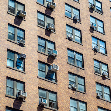 Stock image of window air conditioning units lining building windows.