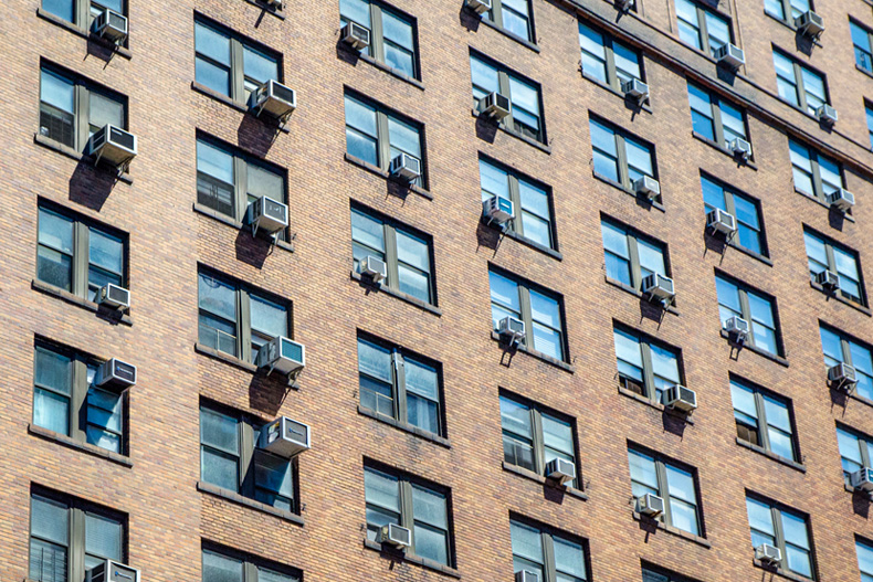 Stock image of window air conditioning units lining building windows.