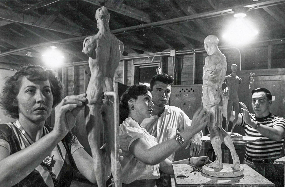 Three students and instructor sculpting clay models of the human body. Photo: University Archives