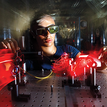 Kayla Spencer, a graduate student in the Department of Physics at the College of Arts and Sciences, uses a laser to calibrate micropore X-ray optics in professor Massimiliano Galeazzi’s astrophysics laboratory in the James L. Knight Physics Building.