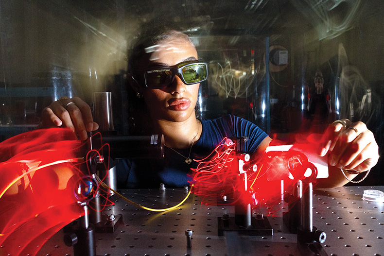 Kayla Spencer, a graduate student in the Department of Physics at the College of Arts and Sciences, uses a laser to calibrate micropore X-ray optics in professor Massimiliano Galeazzi’s astrophysics laboratory in the James L. Knight Physics Building.