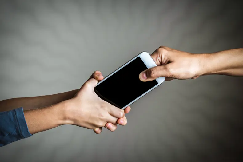 Stock image of hands fighting for a mobile device 