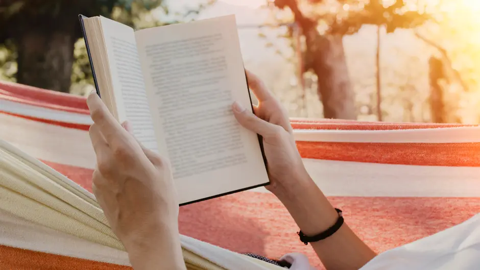 Person laying in a hammock reading a book