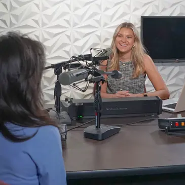 Students record a podcast episode in a studio. 
