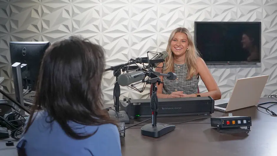Students record a podcast episode in a studio.