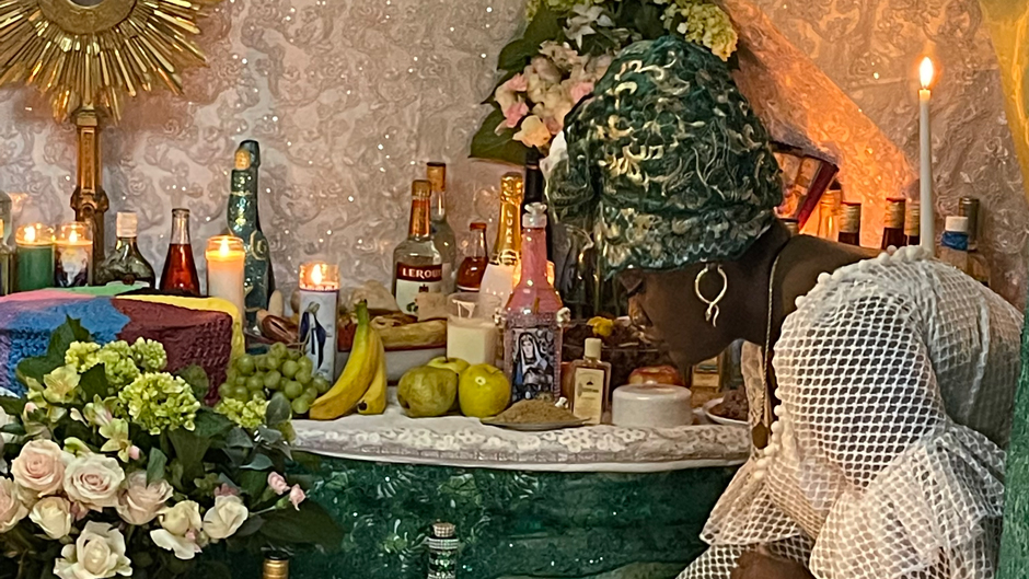 Manbo Cynthia places a cup of water on an altar during a Vodou ceremony 