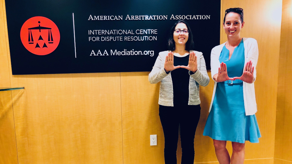 Two lawyers in front of American Arbitration Association sign