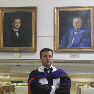 Tanner Stiehl in front of his great-great-grandfather and great-grandfather's portraits