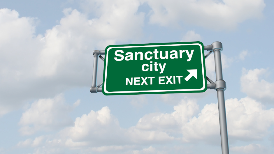Road sign that reads "Sanctuary City, Next Exit"